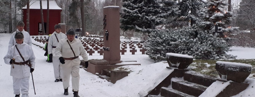 Kuvassa lumipukuisia reserviläisiä marssimassa kohti Sankarihautausmaan muistomerkkiä.