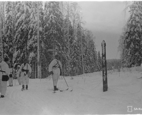 Mustavalkoisessa kuvassa lumipukuisia sotilaita