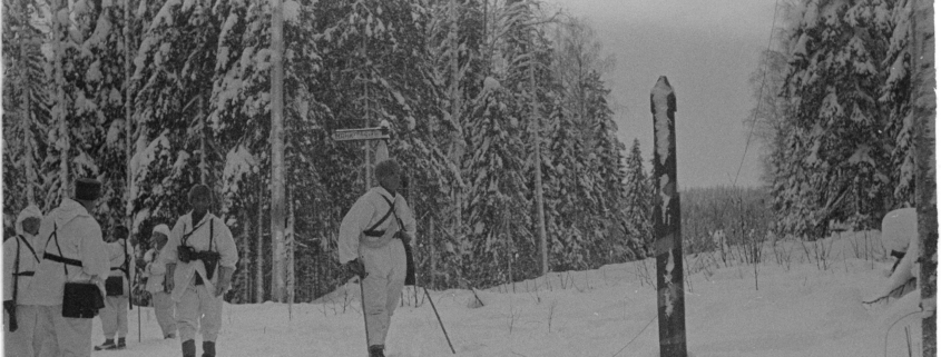 Mustavalkoisessa kuvassa lumipukuisia sotilaita