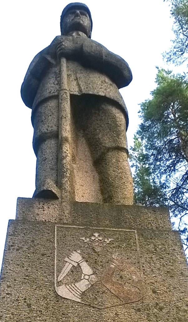 kuvassa suojeluskuntapukuista sotilasta esittävä patsas kivääri jalalla. Jalustassa Karjalan vaakuna.