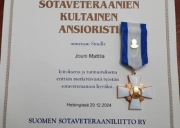 Kuvassa kultainen ansioristi ja myöntökirja