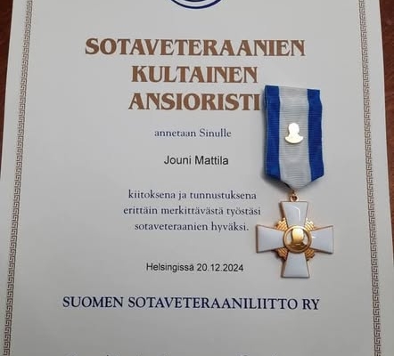 Kuvassa kultainen ansioristi ja myöntökirja