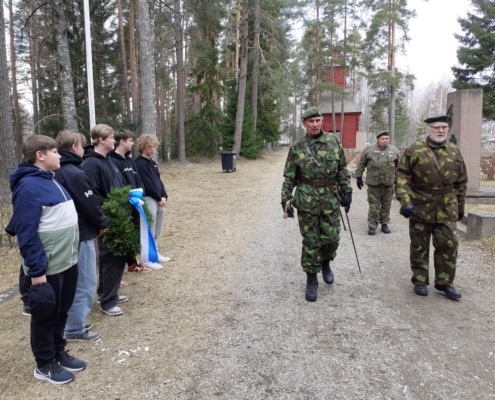 Kuvassa kunniavartio saapuu sankarihautausmaalle yleisön seuratessa.