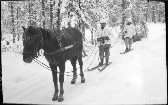 Kuvassa sotilaita suksilla hevosen perässä.