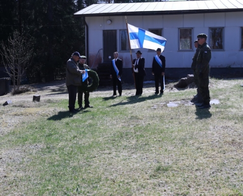 Kuvassa seppeleenlaskijat, Suomen lippu airueineen ja kunniavartio.