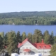 Kuvassa kansallisromanttinen puurakennus, jonka taustalla järvi ja vaaroja.