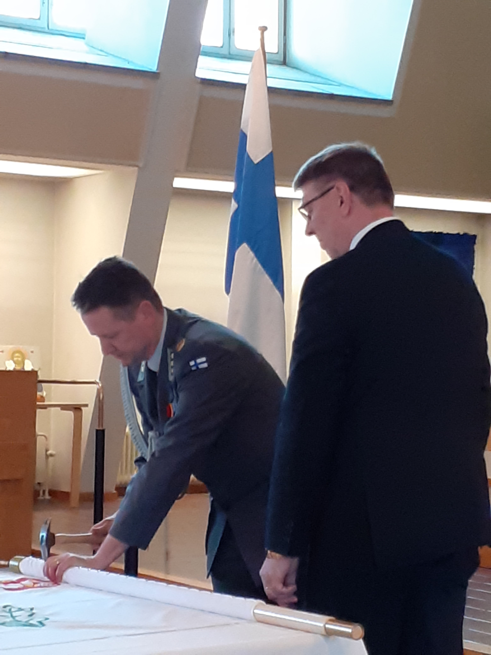Kuvassa mieshenkilöt lipun äärellä.