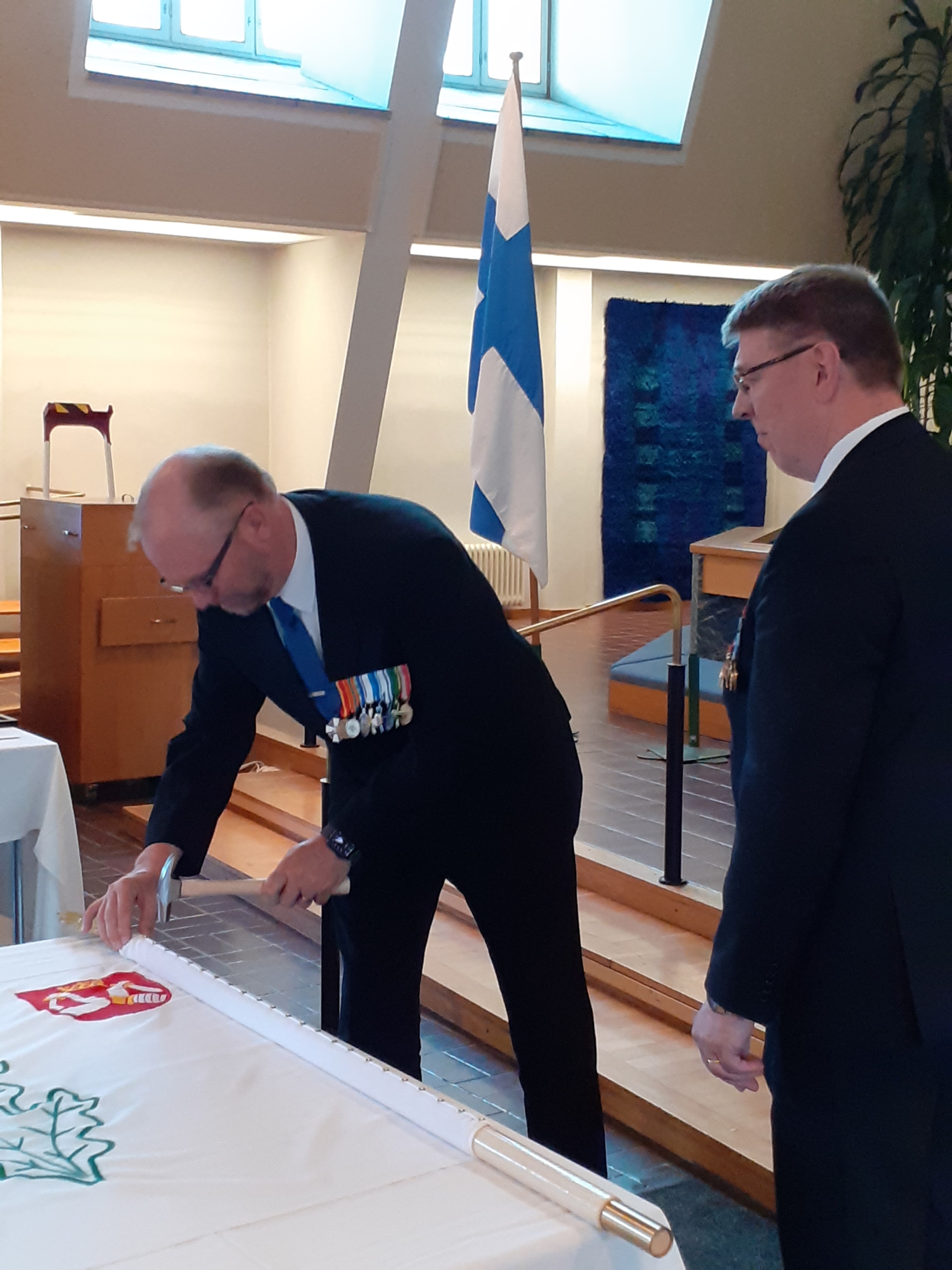 Kuvassa mieshenkilöt lipun äärellä.