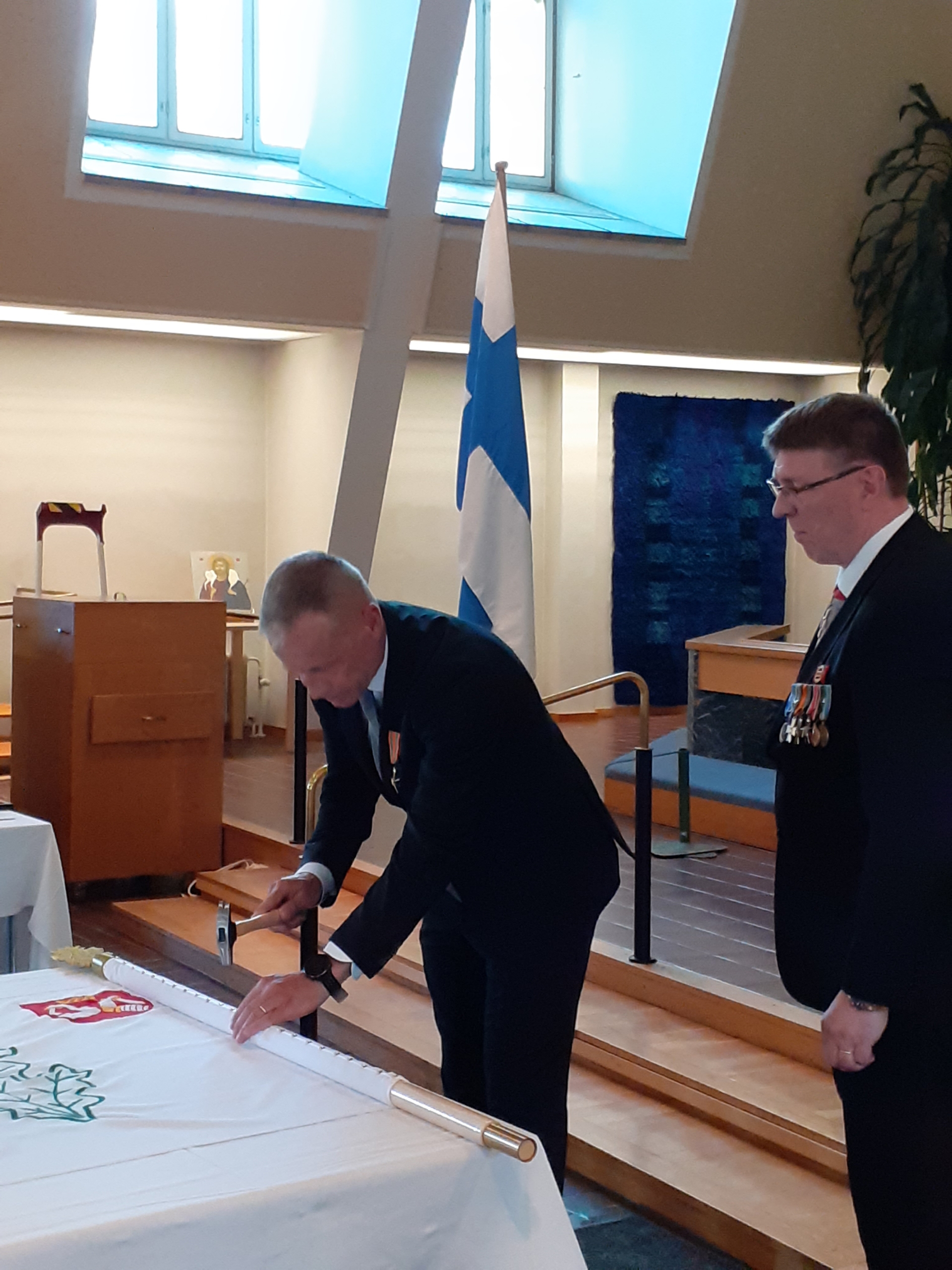 Kuvassa mieshenkilöt lipun äärellä.