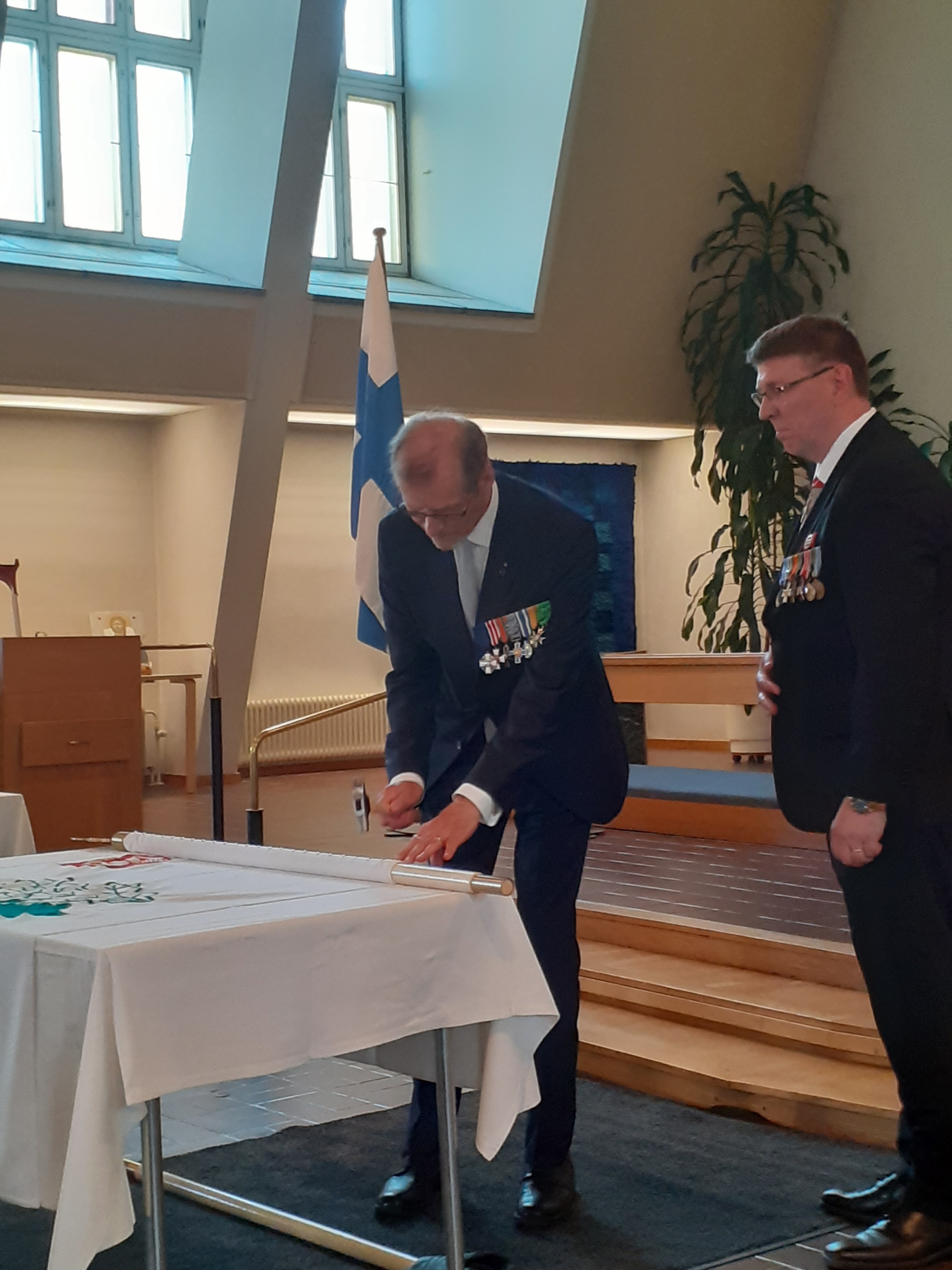 Kuvassa mieshenkilöt lipun äärellä.