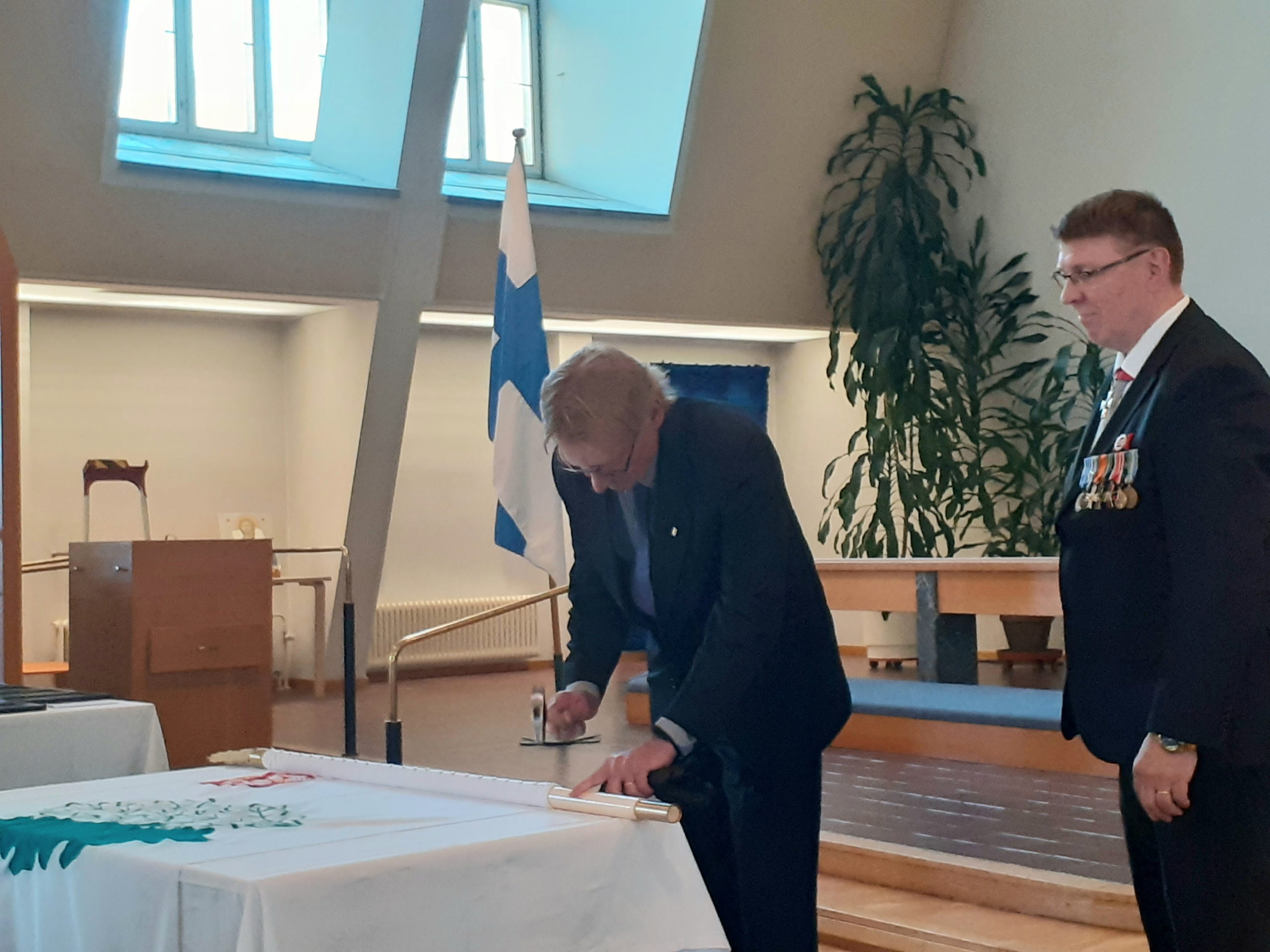 Kuvassa mieshenkilöt lipun äärellä.