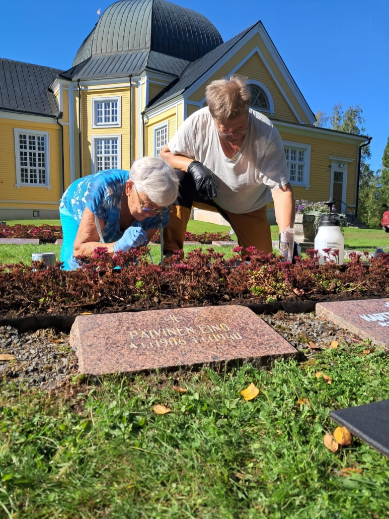 Kuvassa kaksi henkilöä ehostamassa muistokiveä.