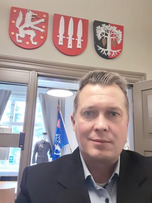 Kuvassa mieshenkilö. Taustalla kuntavaakunoita.