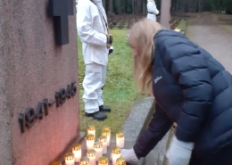 Kuvassa lasketaan kynttilä sankarihaudan muistomerkille. Taustalla kunniavartio.