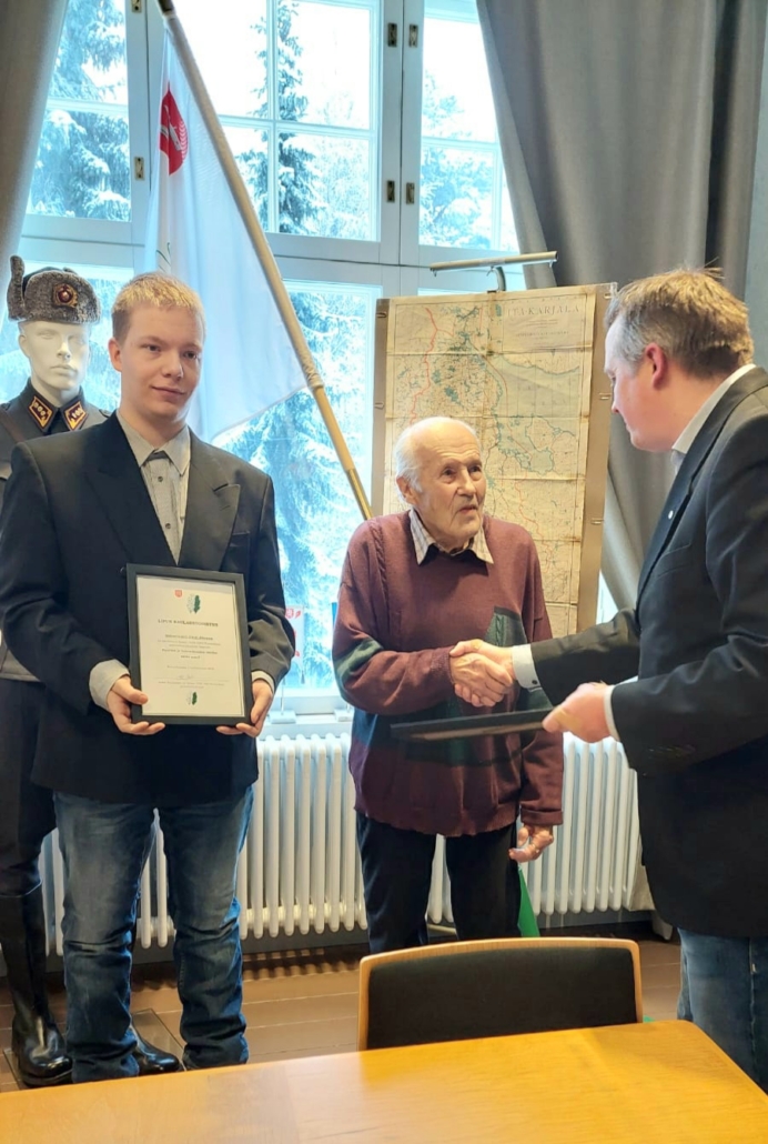 Kuvassa kahdelle mieshenkilölle luovutetaan naulaustodistukset.
