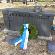 Kuvassa hautamuistomerkki, jonka päällä sotilaskypärä.
