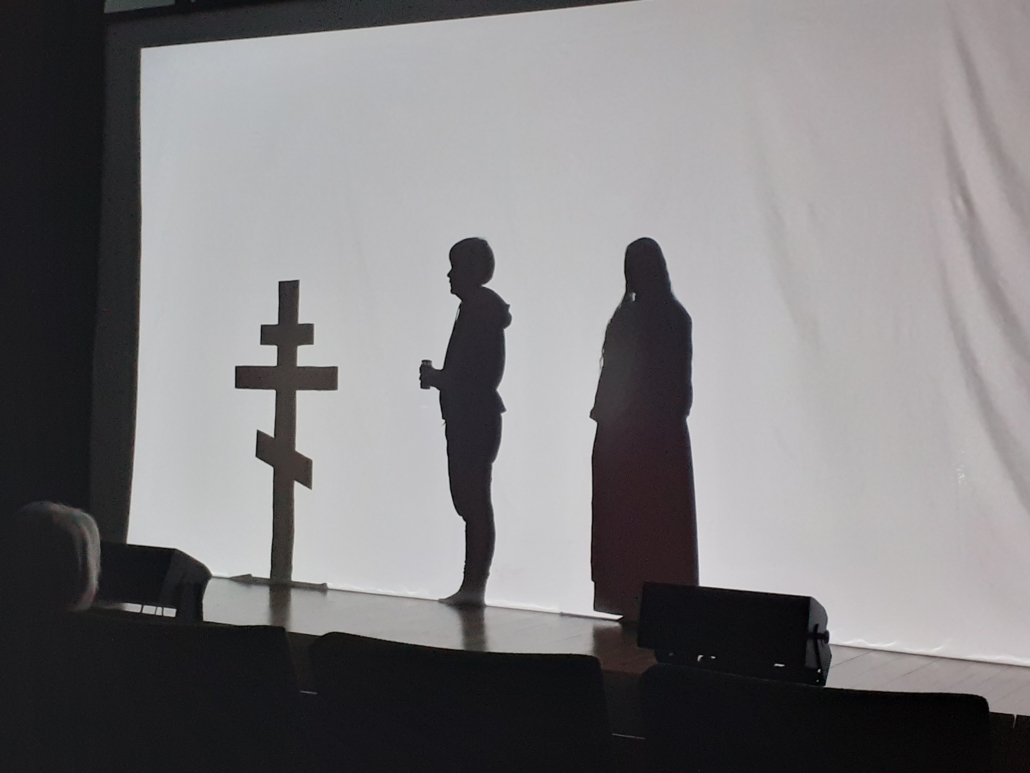 Kuvassa ortodoksiristi ja esiintyjiä teatteriesityksessä.