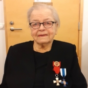 Kuvassa naispuolinen veteraani, kunniamerkit rinnassa.