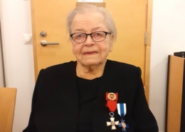 Kuvassa naispuolinen veteraani, kunniamerkit rinnassa.
