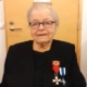 Kuvassa naispuolinen veteraani, kunniamerkit rinnassa.