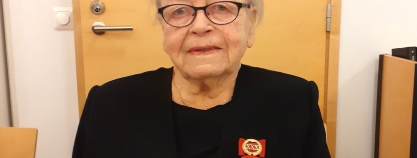 Kuvassa naispuolinen veteraani, kunniamerkit rinnassa.